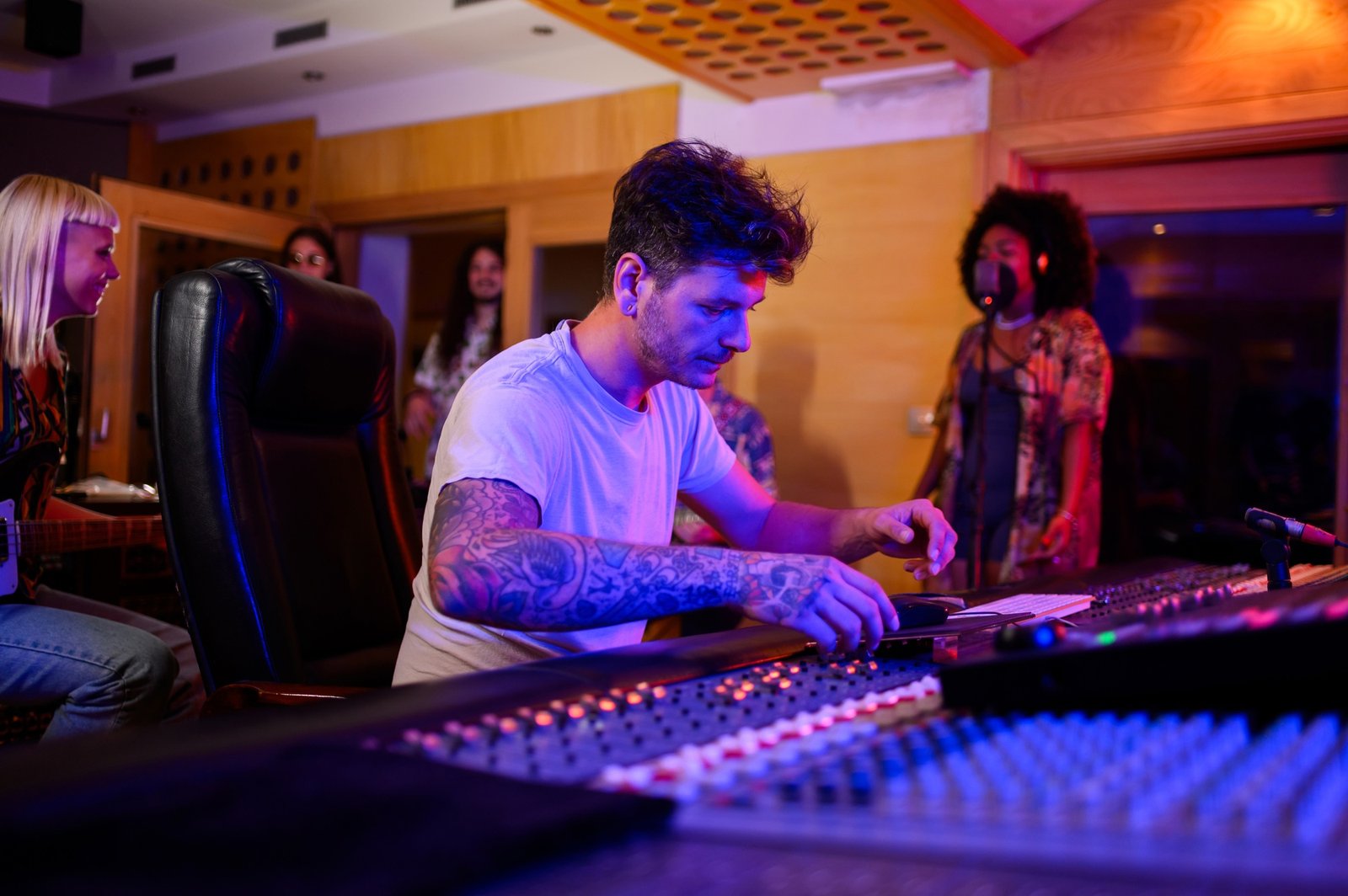 Audio music producer operating on a mixing console in a music studio.